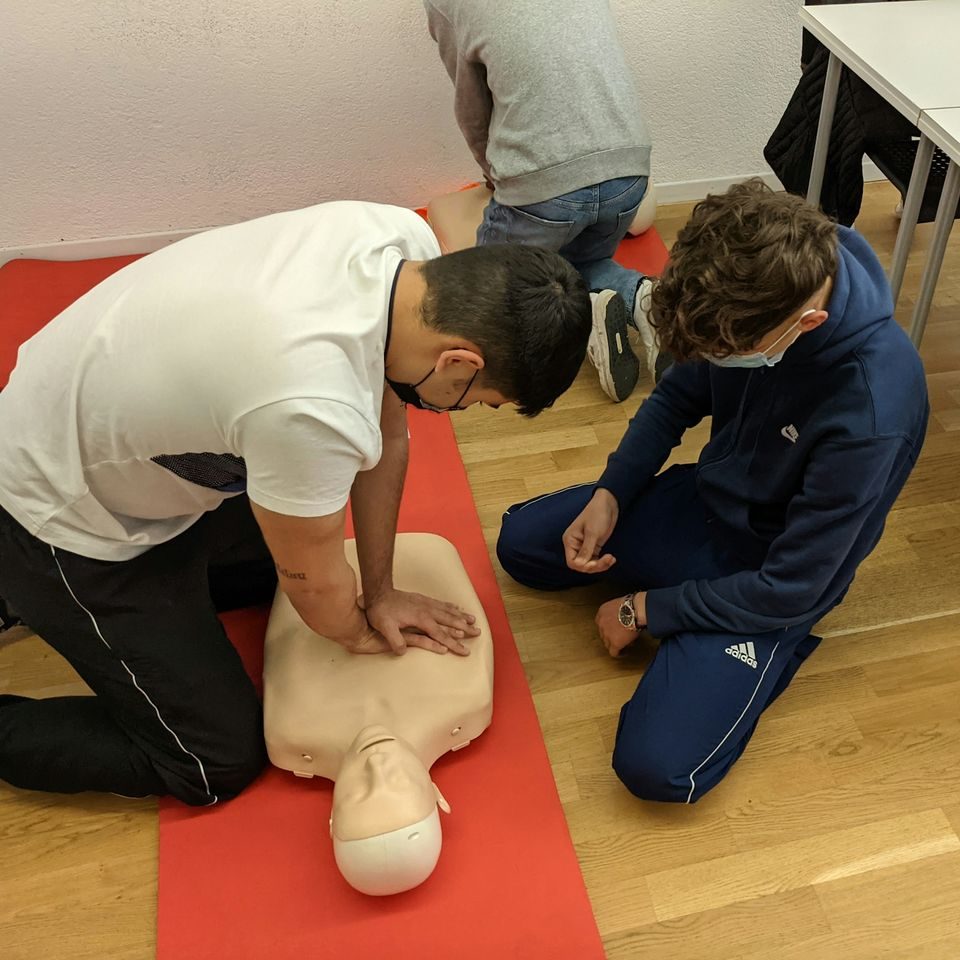 Interessierte jugendliche vertiefen ihre Kenntnisse in der ersten Hilfe und üben die Reanimation an einer Puppe.