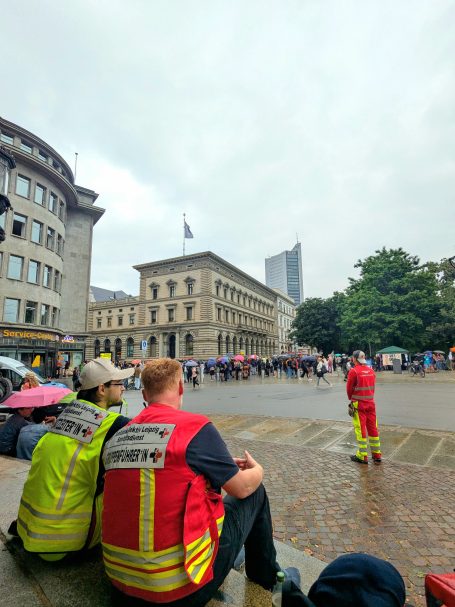 2 Sanitäter*innen mit Funktionswesten (gelb: Einsatzleiter*in / rot: Gruppenführer*in) sitzen auf einer Treppe und besprechen sich.