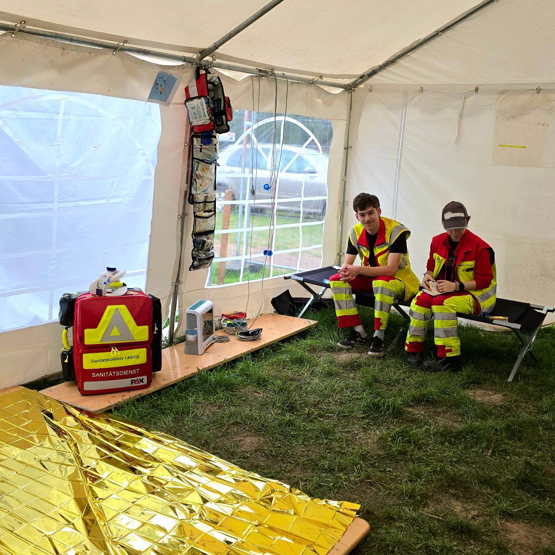Zwei Sanitäter*innen sitzen in der Unfallhilfsstelle, nachdem sie medizinisches Material aufgebaut haben.