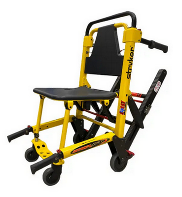 Rettungsstuhl in Orange mit Rädern und Sicherheitsgurten. Er dient dem sitzenden Transport nicht gehfähiger Personen und hat Rollen.