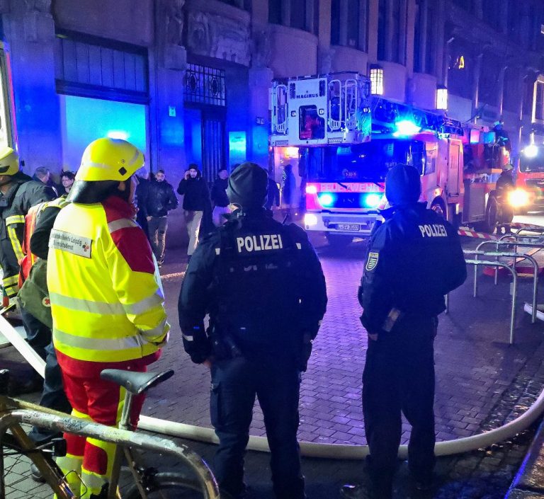 Einsatzkräfte des SKL mit Helm und Einsatzkleidung helfen mit Feuerwehr und Polizei bei einem Gebäudebrand in Leipzig.
