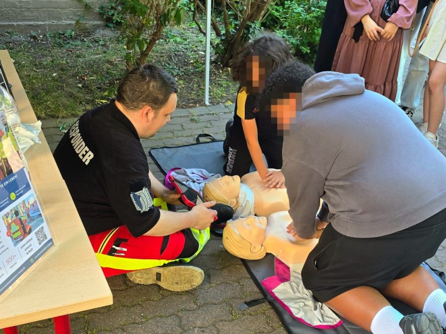 Ein*e Sanitäter*in leitet Schüler*innen bei der CPR-Challange (Reanimationswettbewerb) an und gibt Feedback.