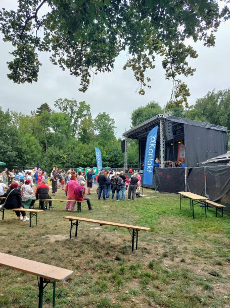 Menschenmenge vor einer Bühne im Freien, umgeben von Bäumen und Ständen. Sie feiern auf dem Schönauer Parkfest 2025.