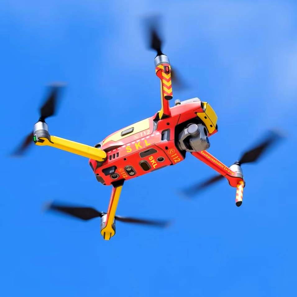 Quadrokopter/Drohne fliegt vor blauem Himmel mit sichtbaren Rotoren. Die Drohne ist als Einsatzfahrzeug des SKL gekennzeichnet.