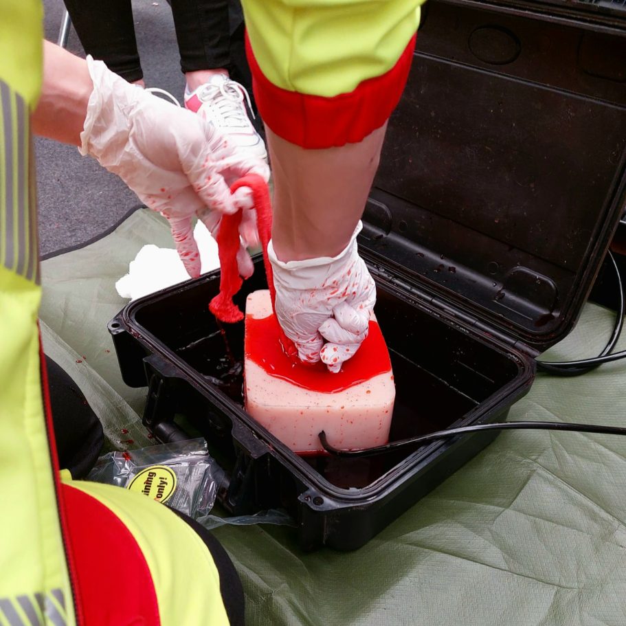 Ein Sanitäter übt an einem Skilltrainer für stark blutende Wunden die schnelle Blutstillung.