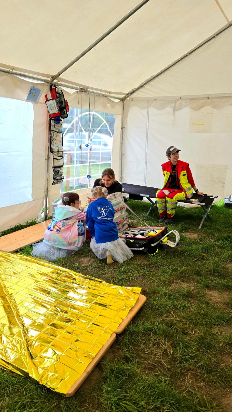 Sanitäter*innen in einer großen Unfallhilfsstelle erklären interessierten Kindern, was sie für Material haben und wie man im Notfall hilft.