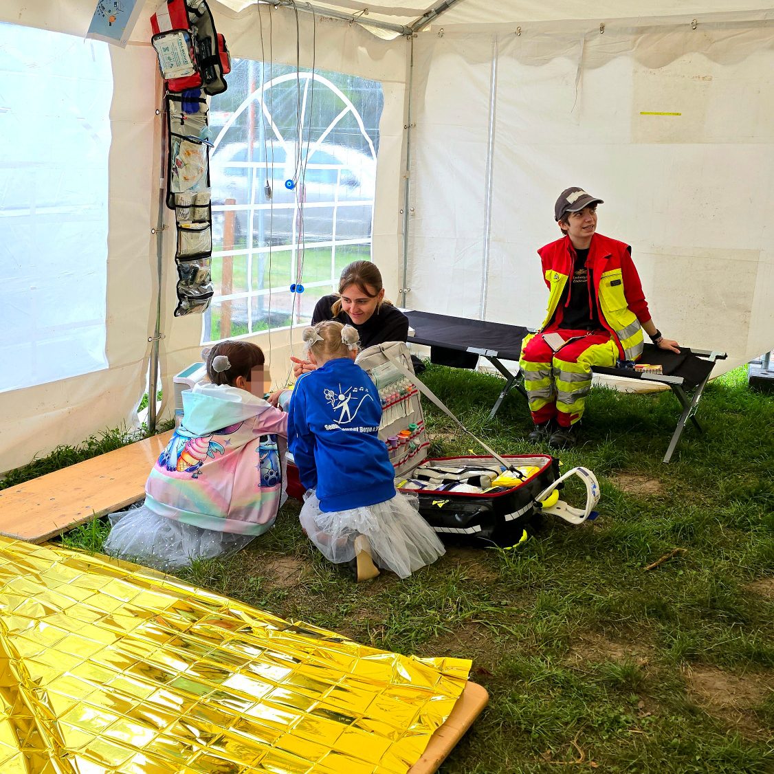 Sanitäter*innen zeigen interessierten Kindern einen Notfallrucksack und erklären diesen, was der Sanitätsdienst macht.