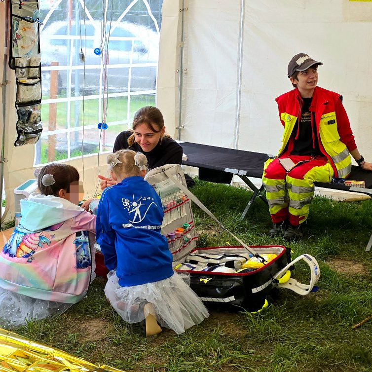 Helfer*innen des Betreuungsdienst zeigen interessierten Kindern, was der Sanitätsdienst macht und wie man sich in Notfällen verhält.