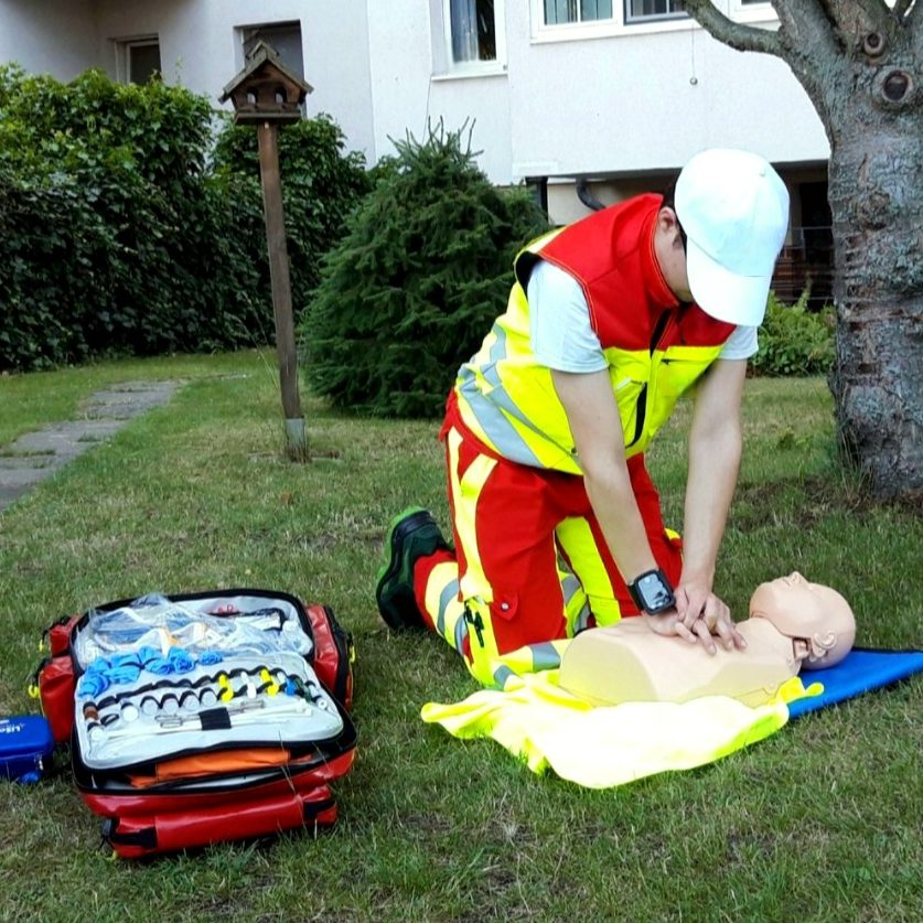 Ein Sanitäter führt die Reanimation an einer Übungspuppe im Freien durch.