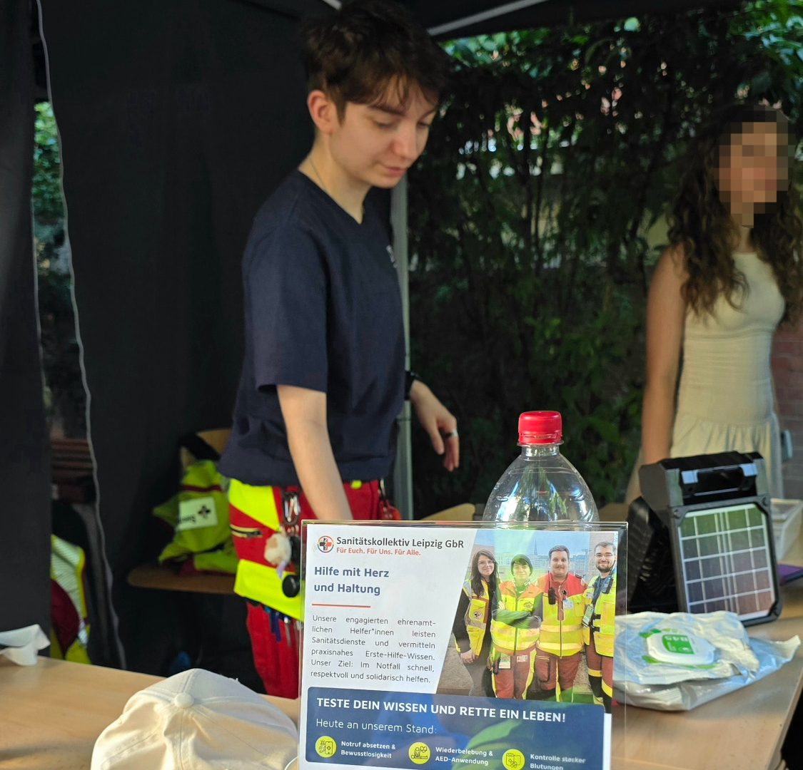 Ein*e Sanitäter*in steht am Eingang der Unfallhilfsstelle (Zelt) bereit und koordiniert die anwesenden Personen.