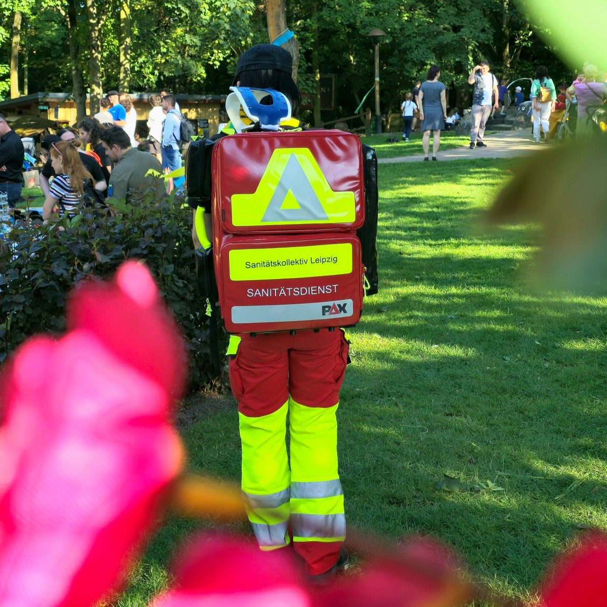 Rettungsdienstmitarbeiter in auffälliger Kleidung mit Rucksack bei der medizinischen Absicherung einer Spendengala.